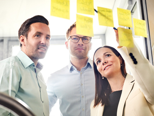 TriFinance Workshop zur Prozessoptimierung: Drei Finance-Experten analysieren Record to Report (R2R) Abl&auml;ufe mittels Post-its in einem modernen B&uuml;ro-Setting.